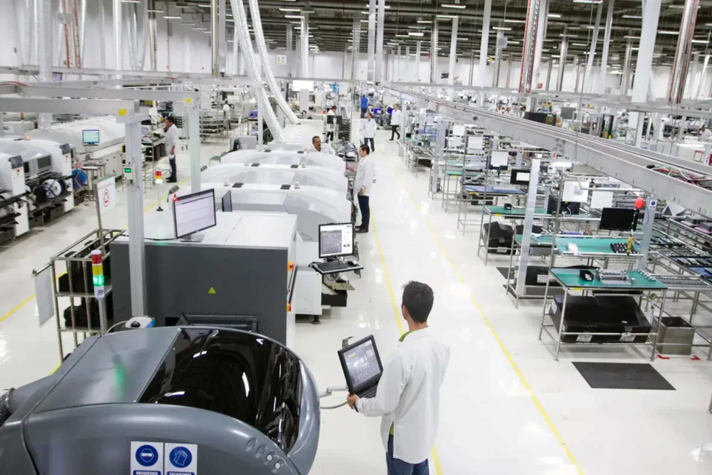 A bright electronics manufacturing floor with production lines and an operator