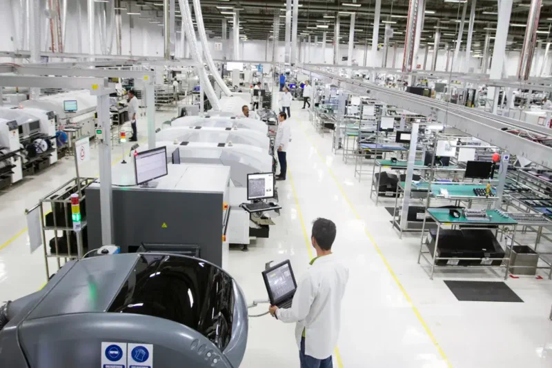 A bright electronics manufacturing floor with production lines and an operator