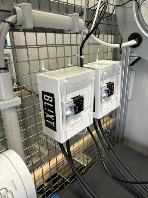 Two Blixt distribution boxes with Zero units installed, mounted on a wire-mesh wall